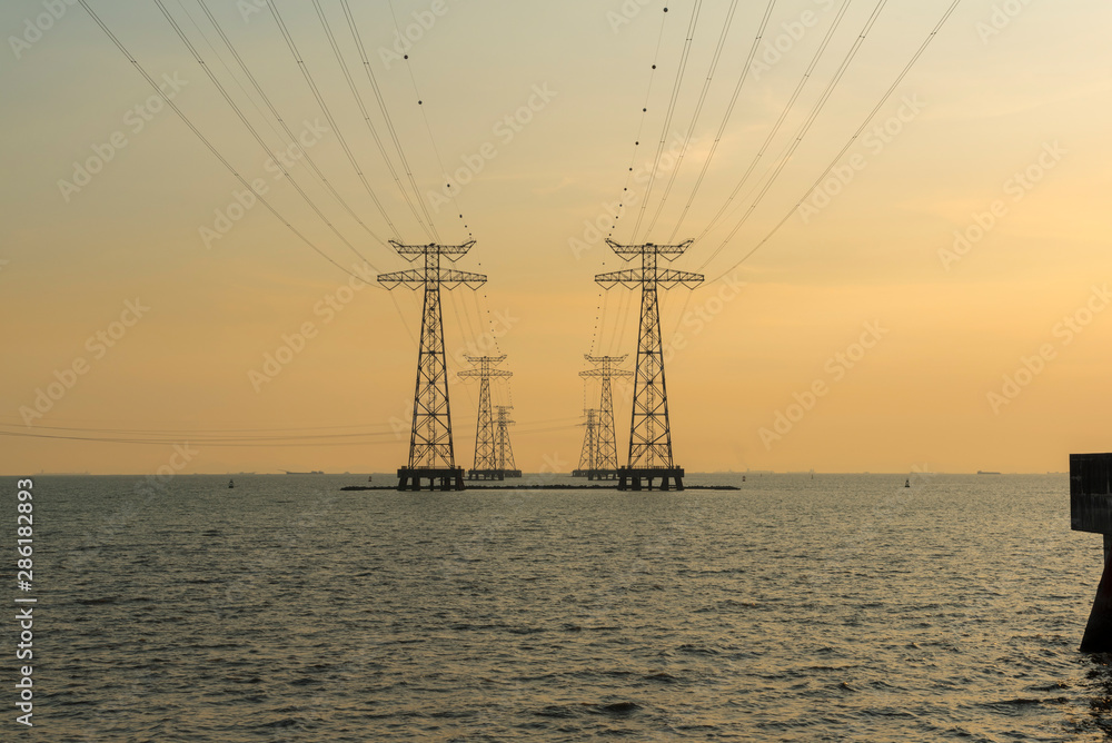 sunset over the sea with a symmetrical power transmission network, photographed in shenzhen, china