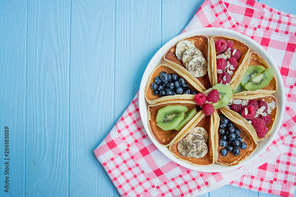 Pancakes with fresh berry on a blue wooden background. Pancakes with fruits. Summer homemade breakfast. Space for text. Blue background.