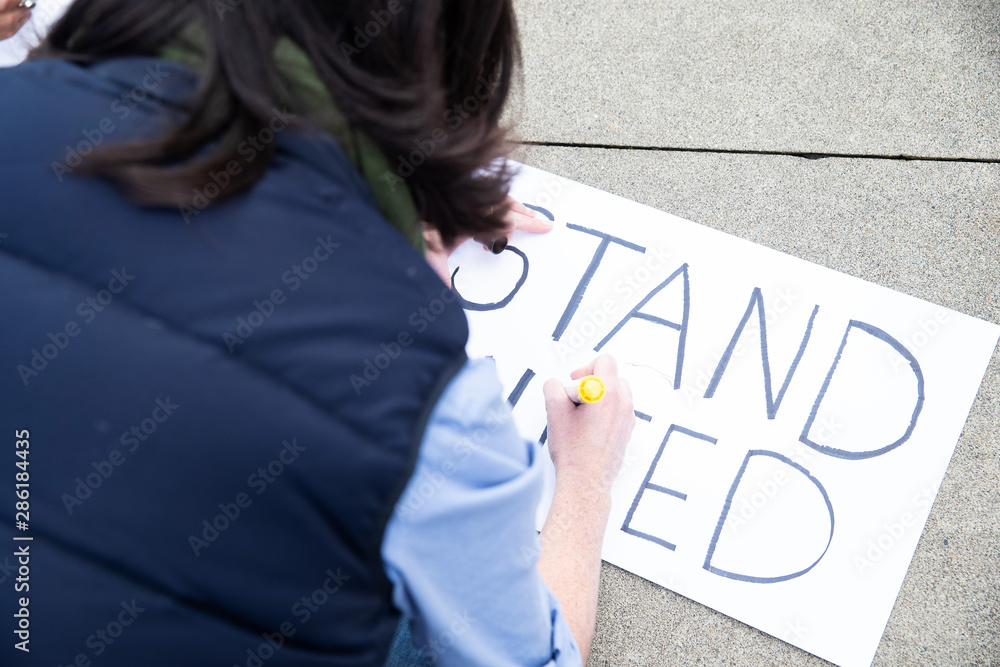 Group of five people protesting outside with signs Group of five people protesting outside with signs