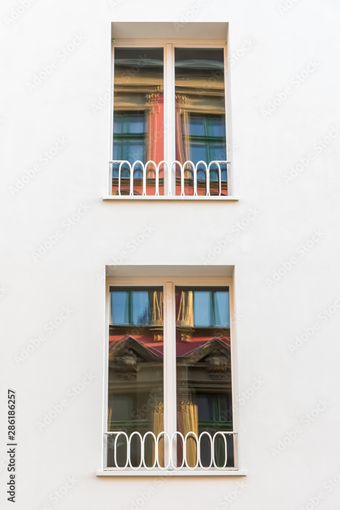 An old residential building is reflected in two windows