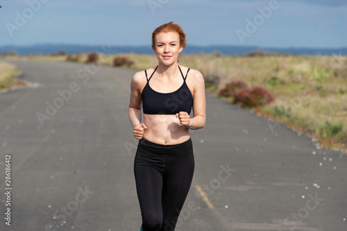 Pretty woman with red hair exercising outside