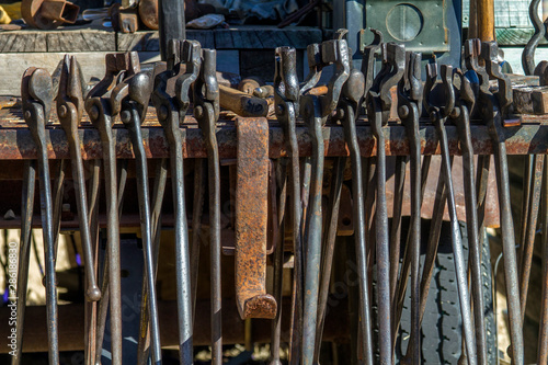 row of blacksmith tools hanging from rack