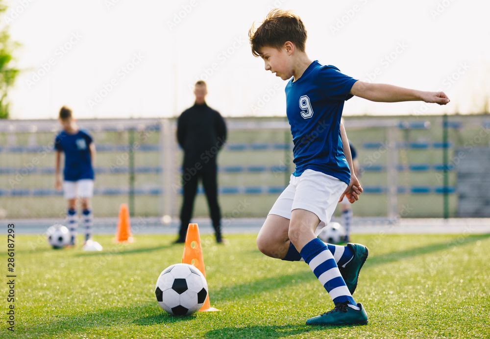 Children training football dribbling in a field. Kids Running the Ball. Players develop soccer dribbling skills. Boys training with balls and cones. Soccer slalom drills Children training football dribbling in a field. Kids Running the Ball. Players develop soccer dribbling skills. Boys training with balls and cones. Soccer slalom drills