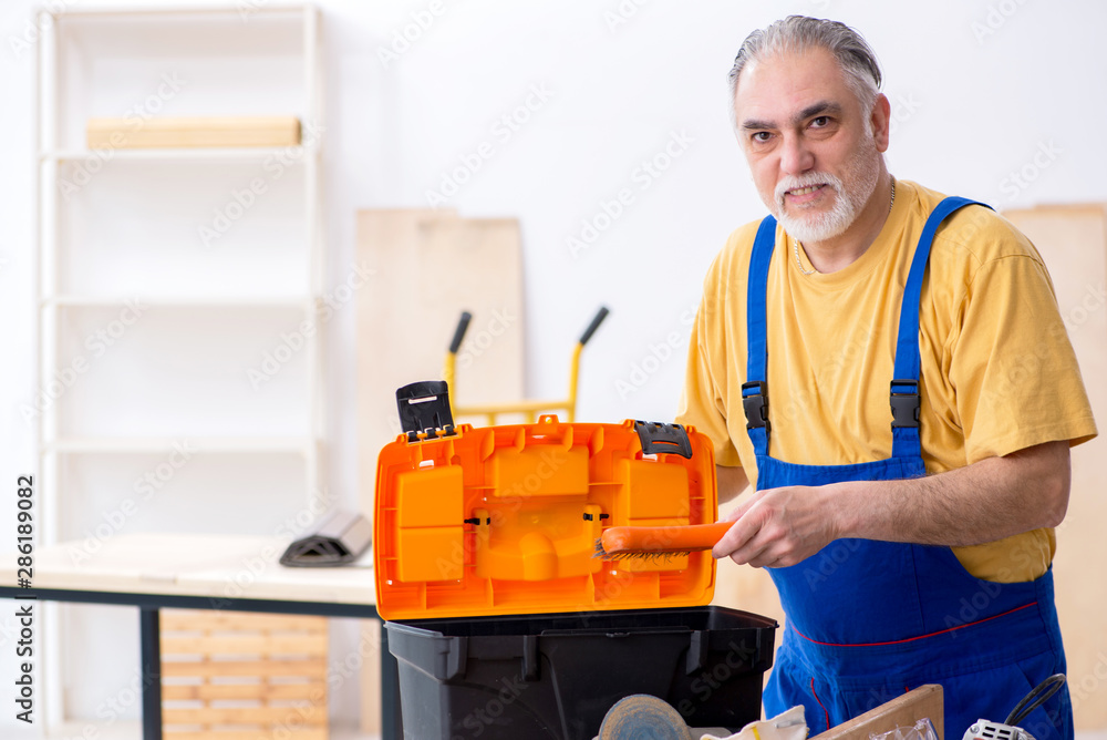 Old male carpenter working in workshop Old male carpenter working in workshop