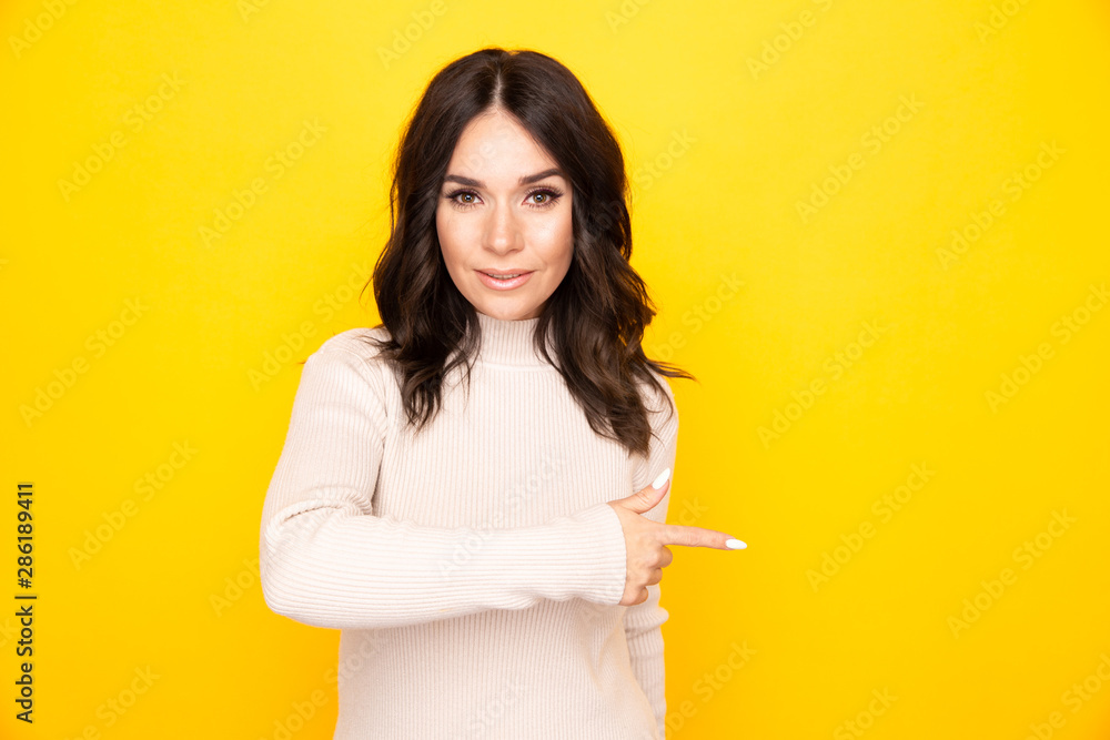 Portrait of female model pointing something isolated the yellow background Portrait of female model pointing something isolated the yellow background