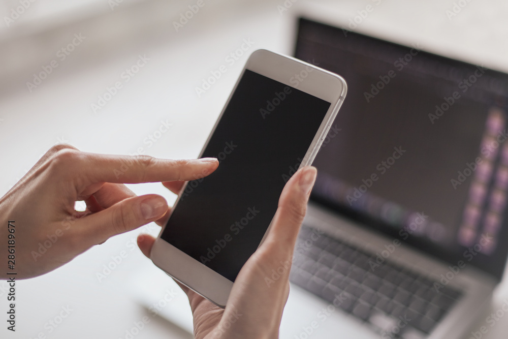 manos de mujer con celular y computadora fuera de foco de fondo. manos de mujer con celular y computadora fuera de foco de fondo.