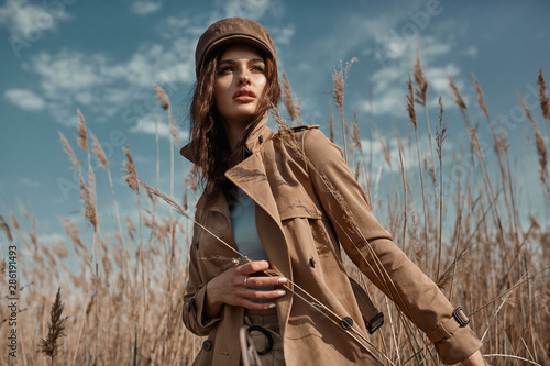 Beautiful Young Stylish Girl in Trench Coat Walking Autumn or Spring street. Autumn outdoor fashion.