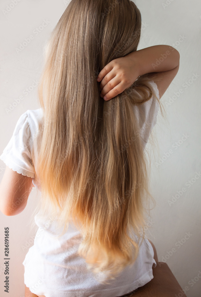 Cute girl with long blond hair. Back view of little girlie looking on side. Isolated on light background. Cute girl with long blond hair. Back view of little girlie looking on side. Isolated on light background.