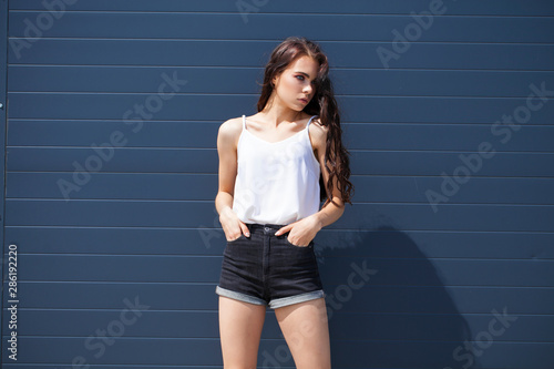 Pretty young brunette model in white summer blouse and jeans, summer street outdoors