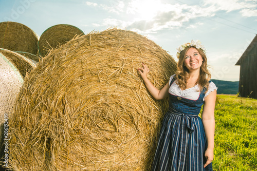 Frau in Tracht vor einem Strohballen an einem sonnigem Tag in bayern photo