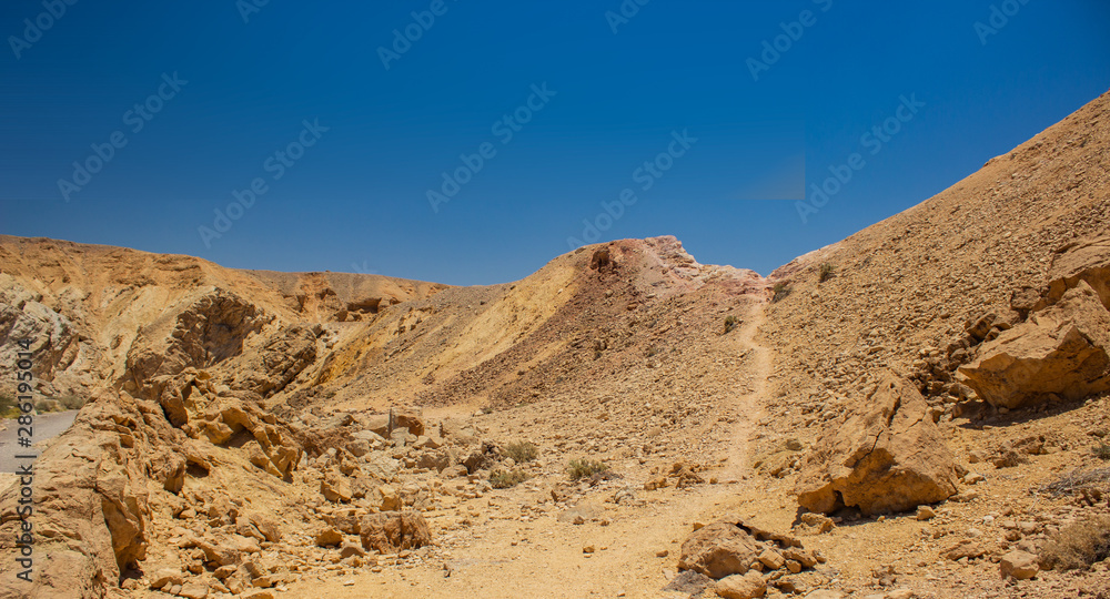 panoramic picture of wilderness dry rocky desert land scenic view with sand stone ground sharp rocks edges and lonely trail 