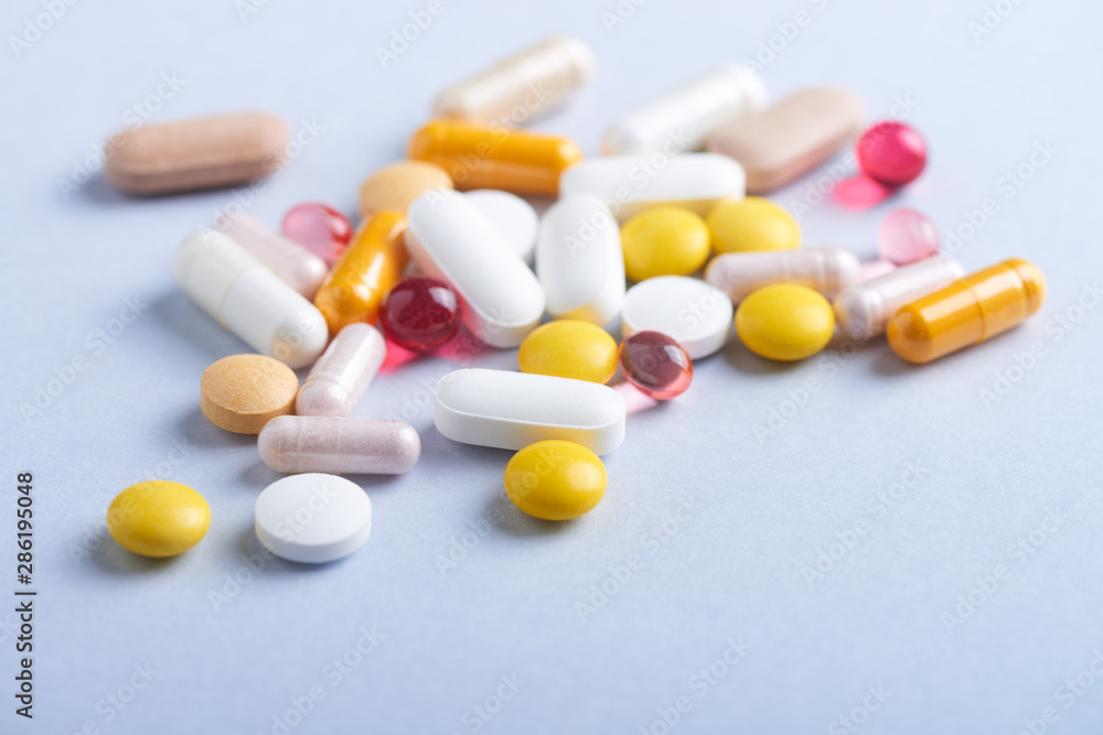 Vitamins and supplements on bright paper background. Concept for a healthy dietary supplementation. Close up. Copy space. 