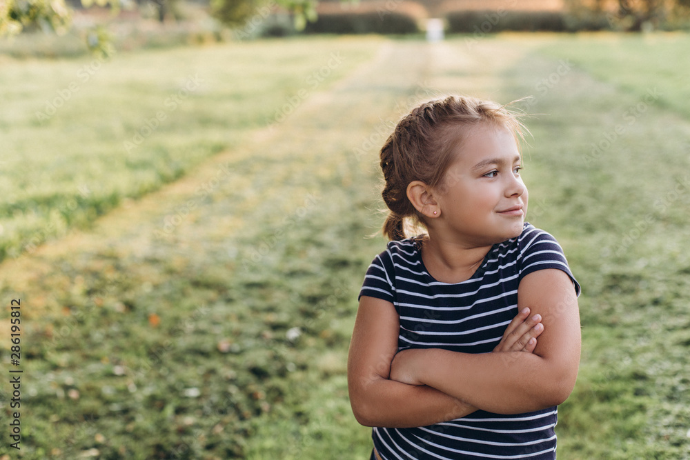 Outdoor portrait of young girl explores the outside world in summer park. Childhood, positive emotions, summer concept Outdoor portrait of young girl explores the outside world in summer park. Childhood, positive emotions, summer concept