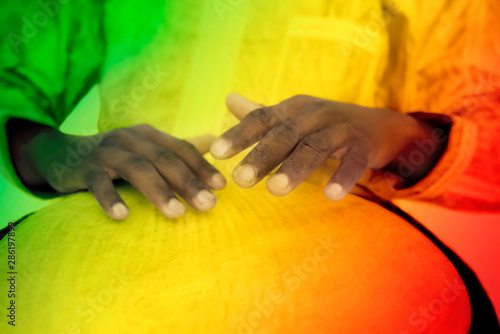 Green, yellow and red photo of a Djembe player using his musical instrument photo