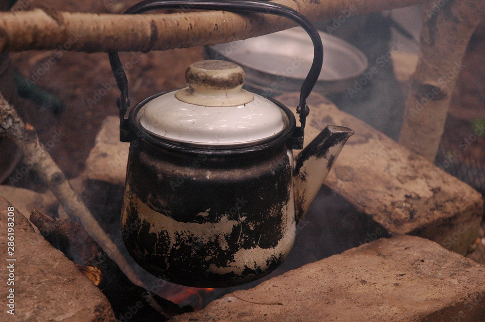 An old teapot on a fireplace in forest An old teapot on a fireplace in forest