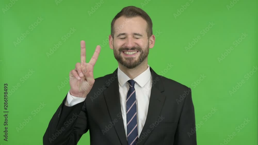 Ambitious Businessman Showing Victory Sign against Chroma Key Ambitious Businessman Showing Victory Sign against Chroma Key