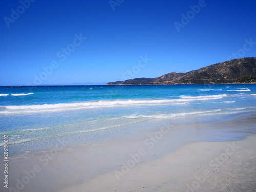 The blue clear water and white sand of a beach in Sardinia.