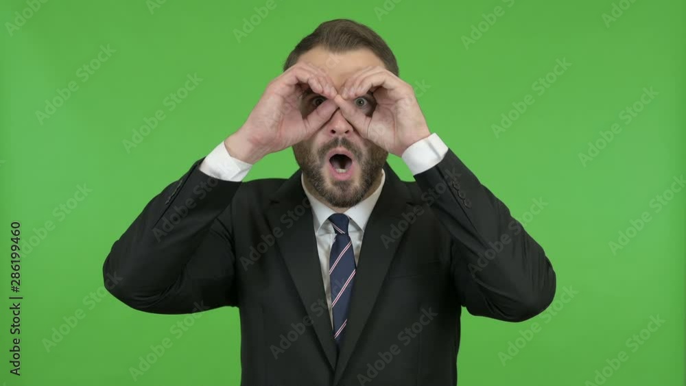 Shocked Businessman looking from Hand Binoculars against Chroma Key Shocked Businessman looking from Hand Binoculars against Chroma Key