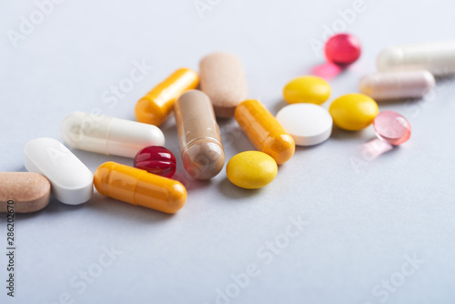 Vitamins and supplements on bright paper background. Concept for a healthy dietary supplementation. Close up. Copy space. 