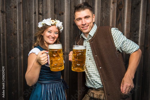 Junge Frau und mann mit Bierkrug und Brezel auf einem Holzhintergrund .Oktoberfest-Konzept  photo