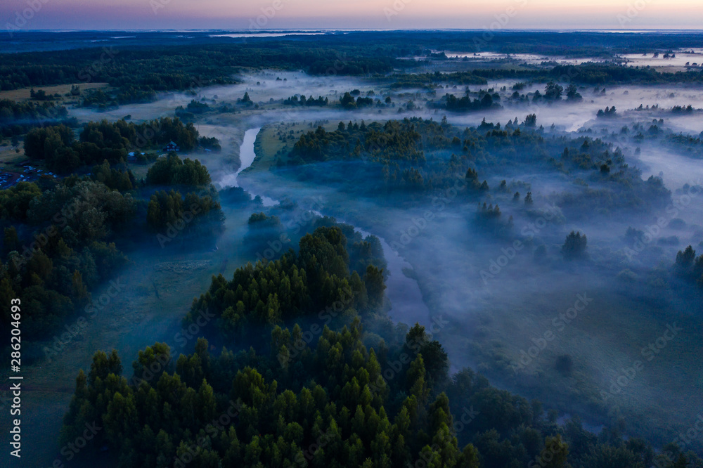 Aerial view of the forest, field and river covered with layers of thick morning fog Aerial view of the forest, field and river covered with layers of thick morning fog