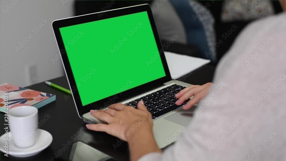 Woman using laptop computer with green screen Woman using laptop computer with green screen