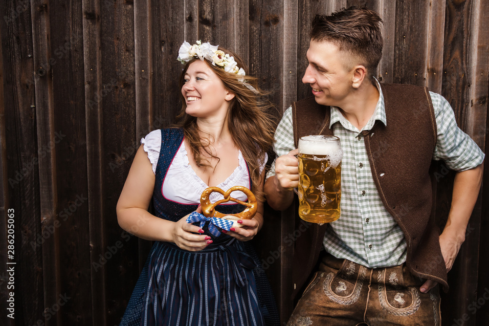 © karepa - Junge Frau und mann mit Bierkrug und Brezel auf einem Holzhintergrund .Oktoberfest-Konzept