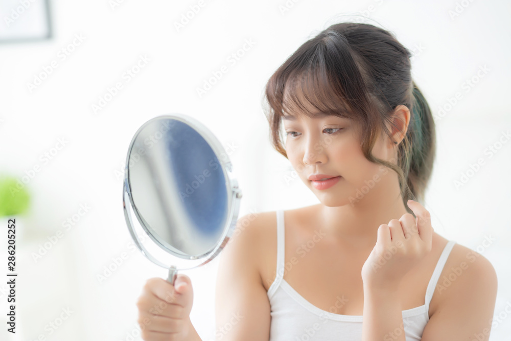 Beautiful young asian woman looking the mirror with acne problem at bedroom, trouble of beauty on face, zit treatment, asia girl is pimple having worry and displeased, skincare and healthy concept.