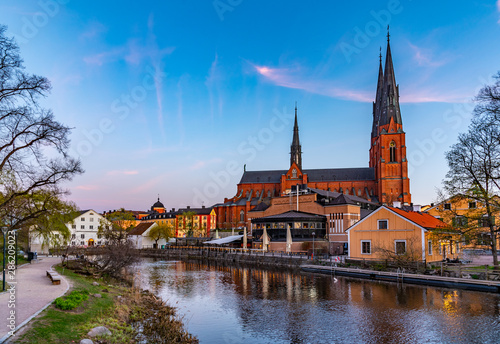 Sunset view of Uppsala cathedral reflecting on river Fyris in Sweden photo