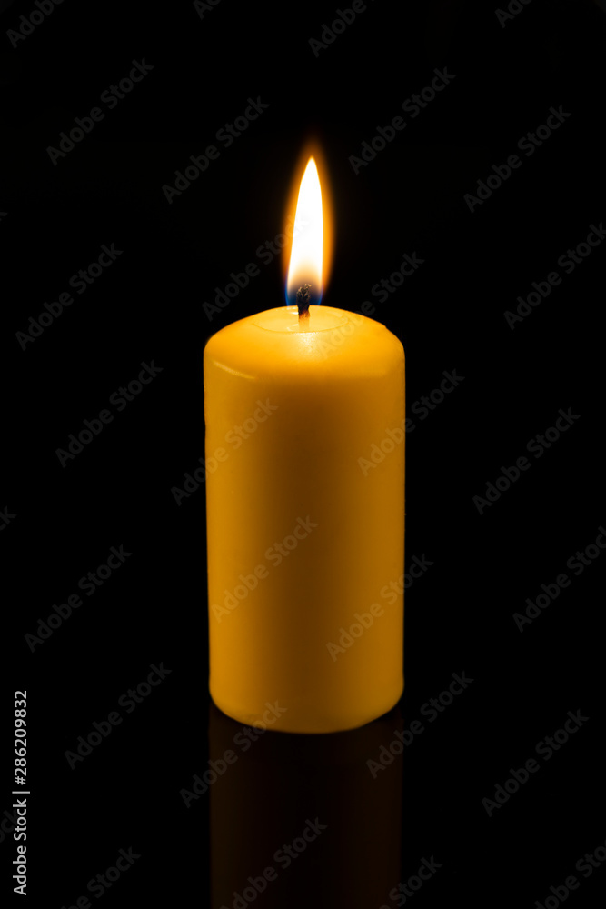 Long, round, yellow wax candles lit on a dark, black background. candle lit  Stock Photo | Adobe Stock