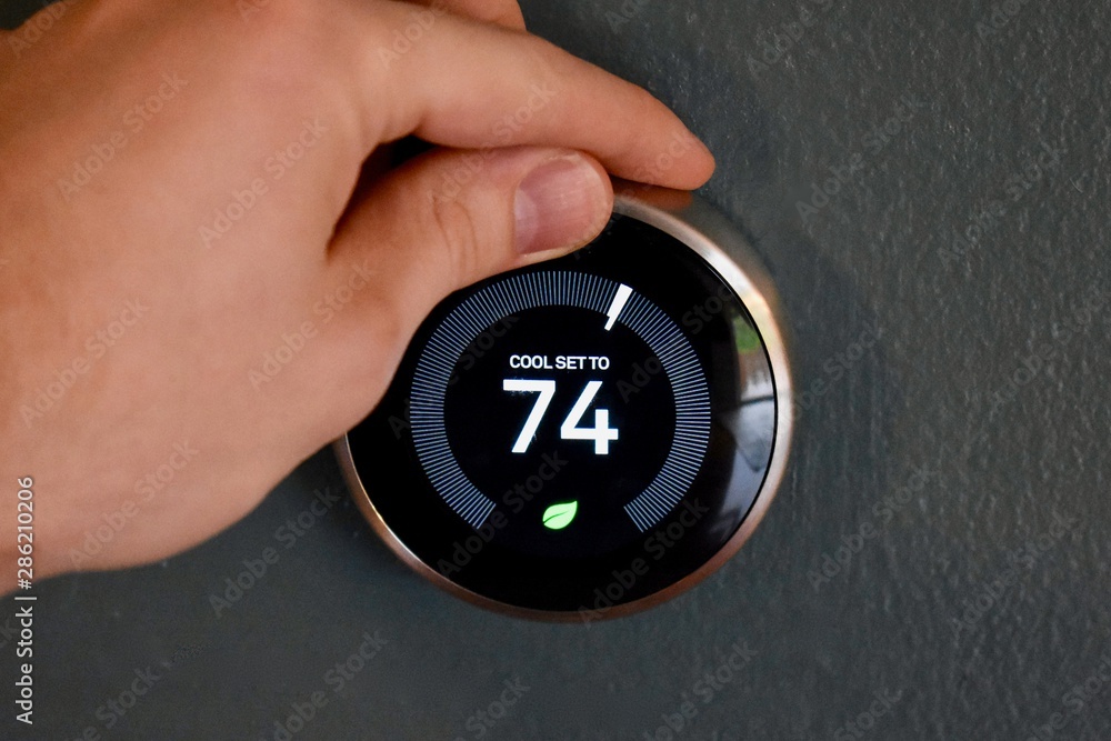 Fotografie Hand adjusting temperature on electric thermostat