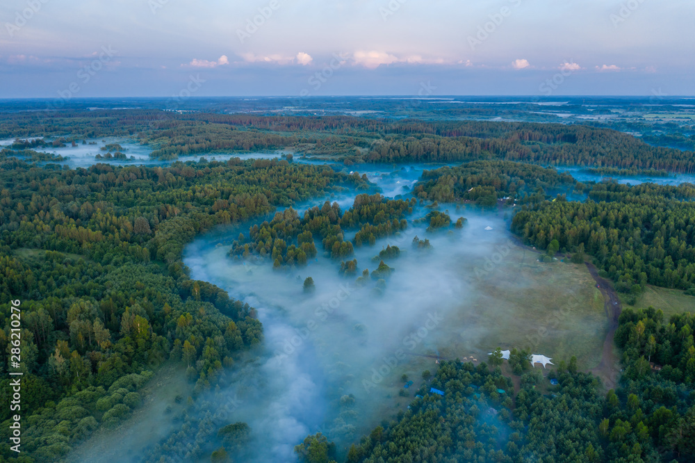 Fog floats over the forest and a field and a star-shaped tent Fog floats over the forest and a field and a star-shaped tent