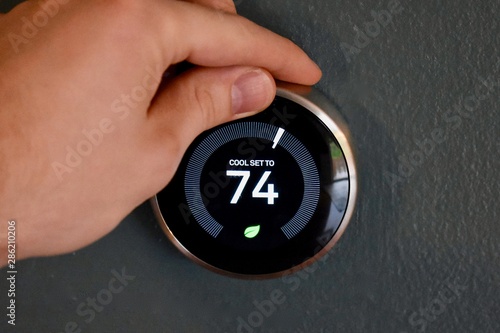 Hand adjusting temperature on electric thermostat
