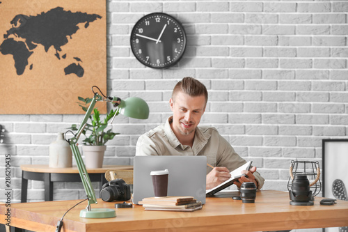 Male blogger with laptop at...