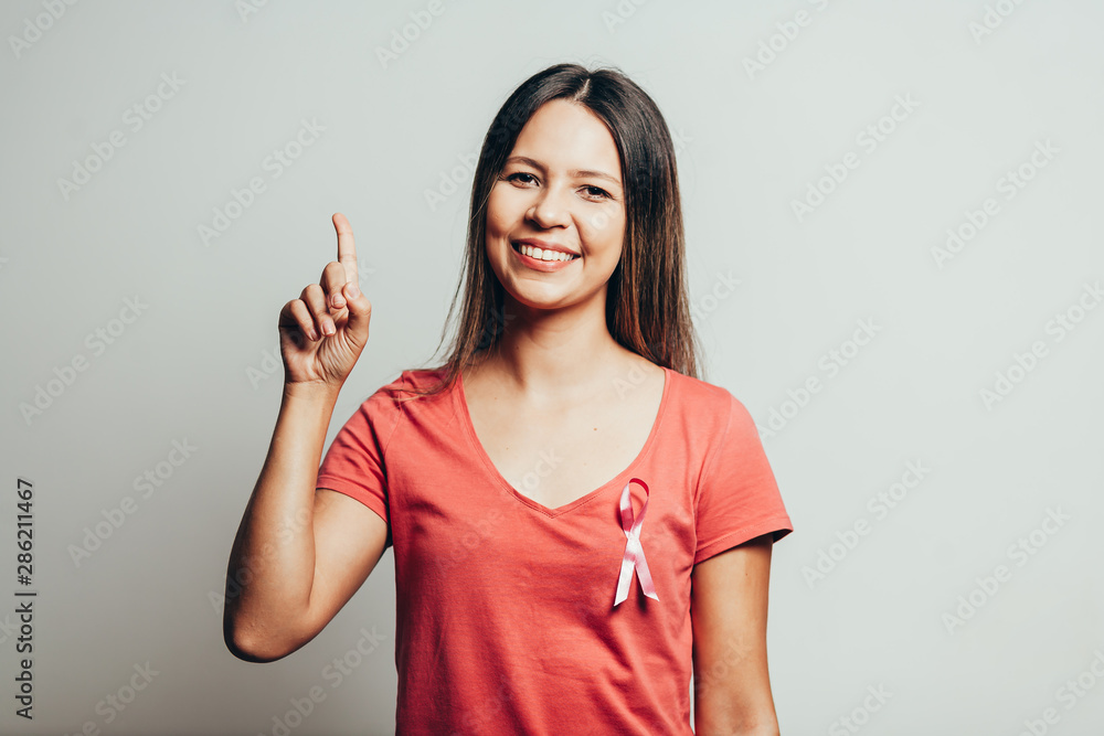 Healthcare and medicine concept - woman in t-shirt with pink breast cancer awareness ribbon Healthcare and medicine concept - woman in t-shirt with pink breast cancer awareness ribbon