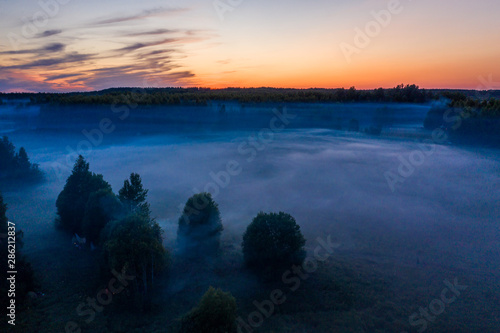 morning fog in layers hangs over the field and forest © alexkazachok