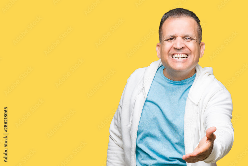 Middle age arab man wearing sweatshirt over isolated background smiling friendly offering handshake as greeting and welcoming. Successful business. Middle age arab man wearing sweatshirt over isolated background smiling friendly offering handshake as greeting and welcoming. Successful business.