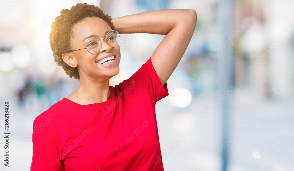 Beautiful young african american woman wearing glasses over isolated background Smiling confident touching hair with hand up gesture, posing attractive