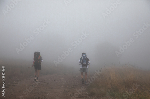 Two backpackers walking into fog