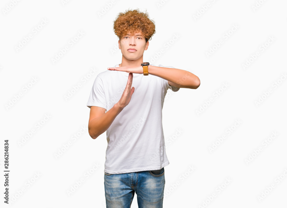 Young handsome man with afro hair wearing casual white t-shirt Doing time out gesture with hands, frustrated and serious face Young handsome man with afro hair wearing casual white t-shirt Doing time out gesture with hands, frustrated and serious face