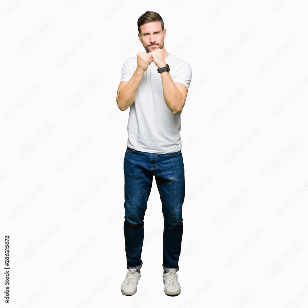 Handsome man wearing casual white t-shirt Ready to fight with fist defense gesture, angry and upset face, afraid of problem Handsome man wearing casual white t-shirt Ready to fight with fist defense gesture, angry and upset face, afraid of problem