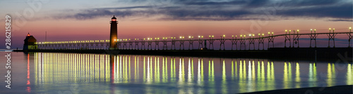 Panorama of Grand Haven Lighthouse at sunset with catwalk lights reflected in Lake Michigan