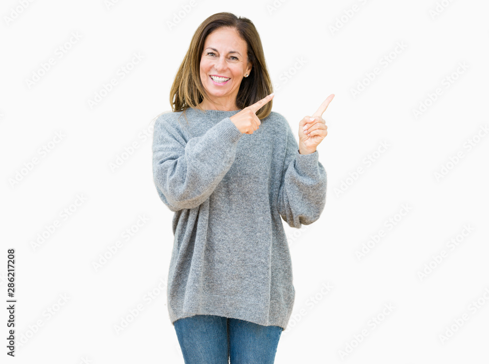 Beautiful middle age woman wearing winter sweater over isolated background smiling and looking at the camera pointing with two hands and fingers to the side. Beautiful middle age woman wearing winter sweater over isolated background smiling and looking at the camera pointing with two hands and fingers to the side.