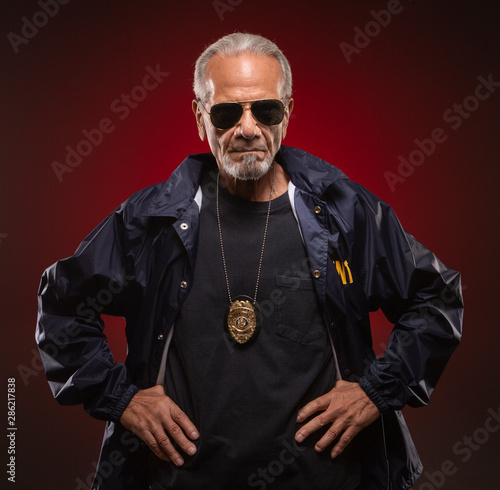 Mature special agent wearing a badge, with his hands on his waist. photo