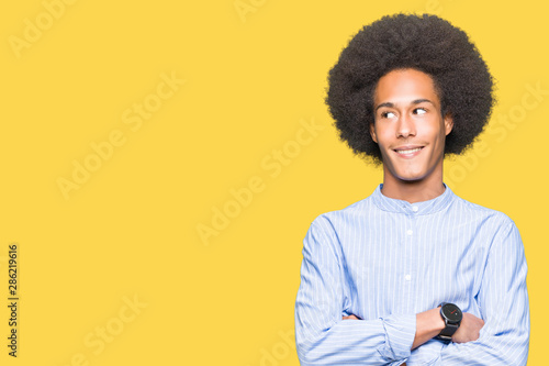 Young african american man with afro hair smiling looking side and staring away thinking.