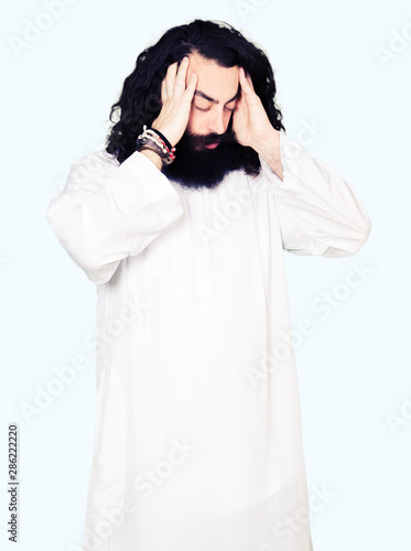 Man wearing Jesus Christ costume with hand on head for pain in head because stress. Suffering migraine.