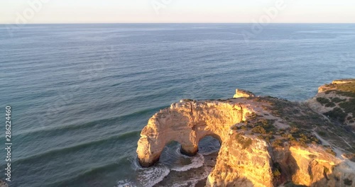 Aerial, drone shot, over the heart shaped sea arch. the Heart rocks, at the Marinha beach, at sunrise, on a sunny, morning dawn, in Carvoeiro, Algarve, Portugal