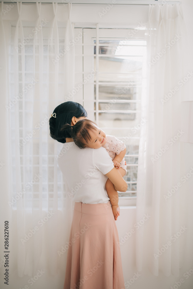 Portrait of happy vietnamese mother hugging with her cute little daughter at home Portrait of happy vietnamese mother hugging with her cute little daughter at home