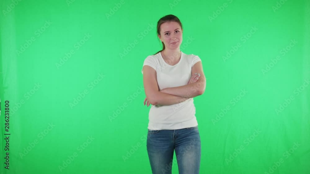Young girl standing with her back to camera is turning keeps her arms crossed Young girl standing with her back to camera is turning keeps her arms crossed