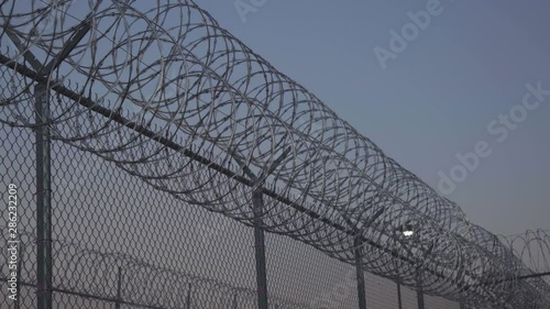 Pan Along Prison Razor Wire at Sunset Outside Jail 4K